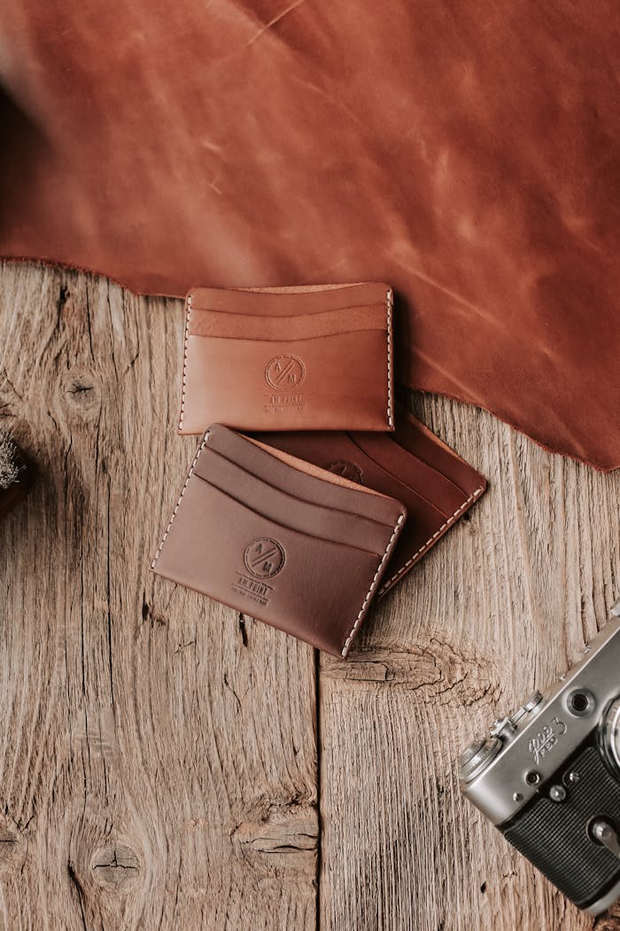 Handmade leather card holders on a wooden surface with vintage camera.